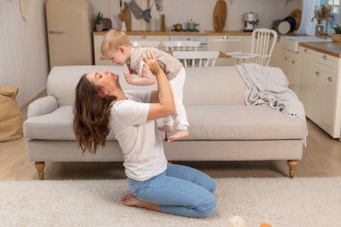 Evde mutlu bir aile. Anne küçük bir çocuğu havadan kaldırıyor. Anne ve bebek evde oyun oynuyorlar. Anne bebeğe sevgiyle sarılır. Küçük anne oğlu oturma odasında dinleniyor.