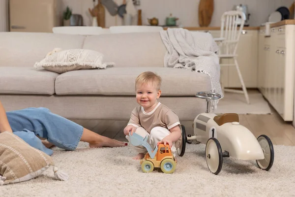 stock image Happy family at home. Baby boy playing with toy car at home indoors. Little toddler child and mother having fun together. Kid son rest in living room