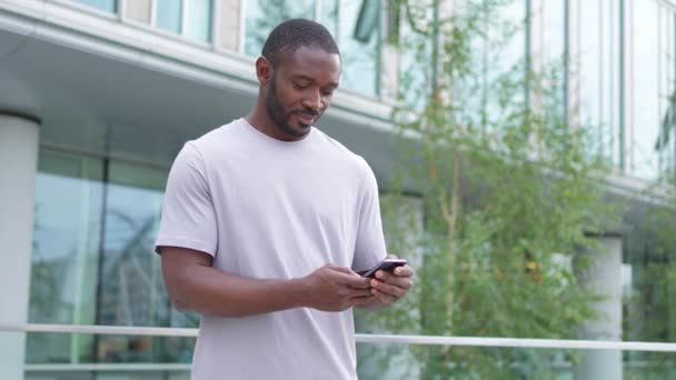 Afroamerikansk Man Håller Smartphone Pekskärm Skriva Skriftrulle Sida Urban Gata — Stockvideo