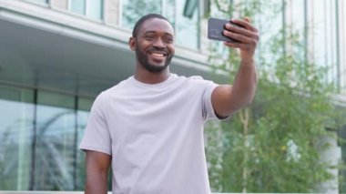Afro-Amerikalı bir adam elinde akıllı telefonuyla şehirdeki bir caddede görüntülü konuşma yapıyor. Blogcu sosyal ağda en iyi arkadaşlarıyla sohbet ediyor. İnternette sanal görüşme yapan bir adam görüntülü konuşma yapıyor.