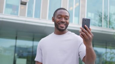 Afro-Amerikalı bir adam elinde akıllı telefonuyla şehirdeki bir caddede görüntülü konuşma yapıyor. Blogcu sosyal ağda en iyi arkadaşlarıyla sohbet ediyor. İnternette sanal görüşme yapan bir adam görüntülü konuşma yapıyor.