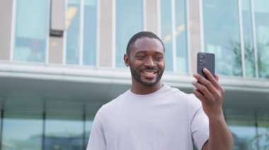 Afro-Amerikalı bir adam elinde akıllı telefonuyla şehirdeki bir caddede görüntülü konuşma yapıyor. Blogcu sosyal ağda en iyi arkadaşlarıyla sohbet ediyor. İnternette sanal görüşme yapan bir adam görüntülü konuşma yapıyor.