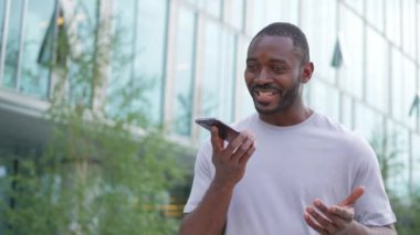 Açık havada, sokakta akıllı telefondan konuşan Afrikalı Amerikalı bir adam. Cep telefonlu bir adam arkadaşlarıyla sohbet ediyor. Gülümseyen kişi cep telefonuyla cevap veriyor. Cep telefonuyla konuşan adam