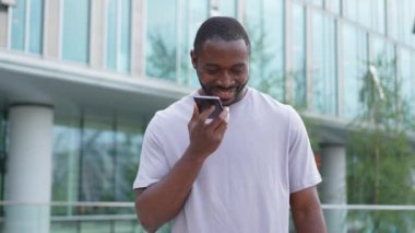 Açık havada, sokakta akıllı telefondan konuşan Afrikalı Amerikalı bir adam. Cep telefonlu bir adam arkadaşlarıyla sohbet ediyor. Gülümseyen kişi cep telefonuyla cevap veriyor. Cep telefonuyla konuşan adam