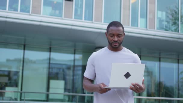 非裔美国人自由职业者在城市街道上使用笔记本电脑打字聊天 有人在网上开虚拟会议聊天 在户外用笔记本电脑工作的企业家程序员 远程工作 — 图库视频影像