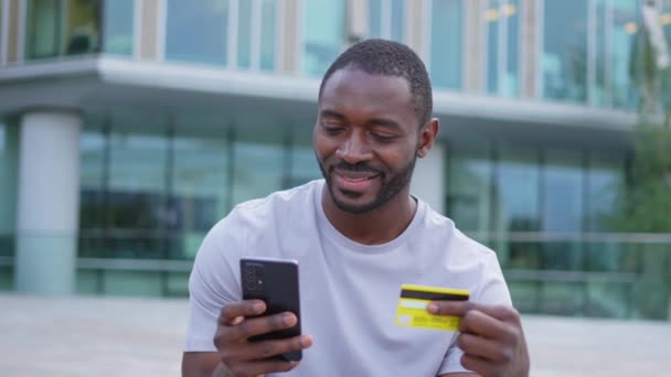 Афроамериканец Совершивший Покупки Онлайн Держит Смартфон Оплачивающий Золотой Кредиткой Гай — стоковое видео