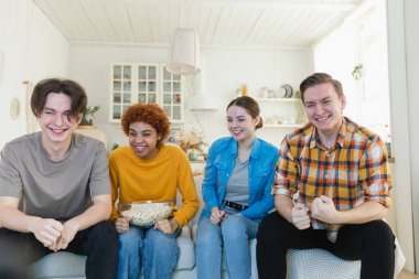 Bir grup arkadaş televizyonda futbol maçı izliyorlar. Memlekette zaferi kutlayan futbol taraftarları. Arkadaşlık sporu eğlence konsepti. Çeşitli arkadaşlar evde birlikte eğleniyorlar.