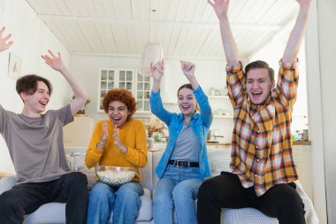Bir grup arkadaş televizyonda futbol maçı izliyorlar. Memlekette zaferi kutlayan futbol taraftarları. Arkadaşlık sporu eğlence konsepti. Çeşitli arkadaşlar evde birlikte eğleniyorlar.