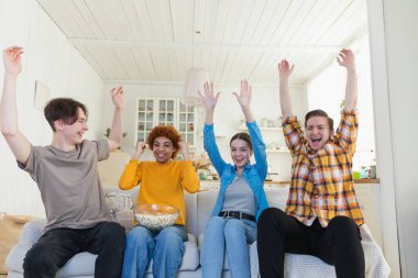 Bir grup arkadaş televizyonda futbol maçı izliyorlar. Memlekette zaferi kutlayan futbol taraftarları. Arkadaşlık sporu eğlence konsepti. Çeşitli arkadaşlar evde birlikte eğleniyorlar.