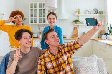 Keyfinize bakın. Mutlu arkadaş grubu selfie çekiyor. Partide arkadaşlarının fotoğrafını çeken bir adam. Telefonda fotoğraf çeken bir grup çok ırklı genç. Gençler gülümsemenin keyfini çıkarırlar.