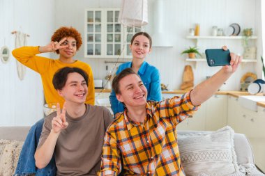 Keyfinize bakın. Mutlu arkadaş grubu selfie çekiyor. Partide arkadaşlarının fotoğrafını çeken bir adam. Telefonda fotoğraf çeken bir grup çok ırklı genç. Gençler gülümsemenin keyfini çıkarırlar.