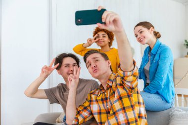 Keyfinize bakın. Mutlu arkadaş grubu selfie çekiyor. Partide arkadaşlarının fotoğrafını çeken bir adam. Telefonda fotoğraf çeken bir grup çok ırklı genç. Gençler gülümsemenin keyfini çıkarırlar.
