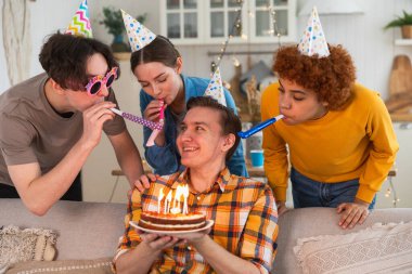 Bir dilek tut. Parti şapkası takmış bir adam doğum günü pastasında yanan mumları üflüyor. Doğum günün kutlu olsun. Arkadaş grubu adama mutlu yıllar diliyor. İnsanlar doğum gününü evde partiyle kutluyor.