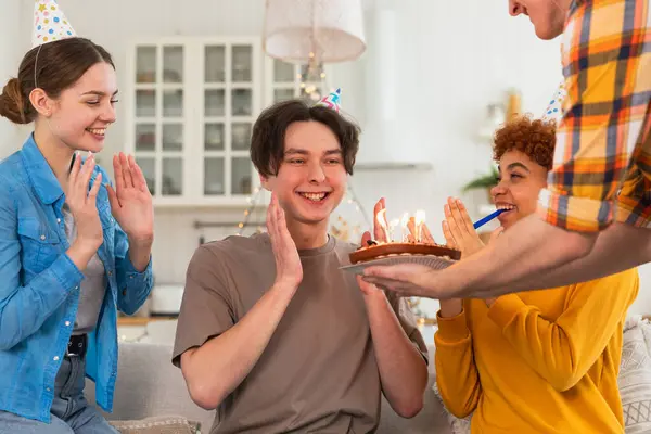 願い事をする 誕生日のケーキにろうそくを吹き飛ばすパーティーキャップを着ている男 ハッピーバースデーパーティー 友人のグループは幸せな誕生日を望んでいます 自宅でパーティーで誕生日を祝う人 — ストック写真