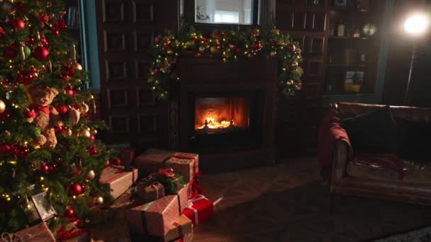 暖炉付きのクラシックなクリスマス装飾インテリアリビングルーム図書館 赤い金色の装飾が施されたクリスマスツリー モダンなクラシックスタイルのインテリアデザインアパートメント 自宅でクリスマスイブ — ストック動画