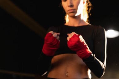 Kadın kendini savunma gücü. Kadın boksör elleri kırmızı boksla sarmalamaya hazırlanıyor sporu koruyan bandajlar. Güçlü eller aktif egzersiz idman antrenmanına hazır.