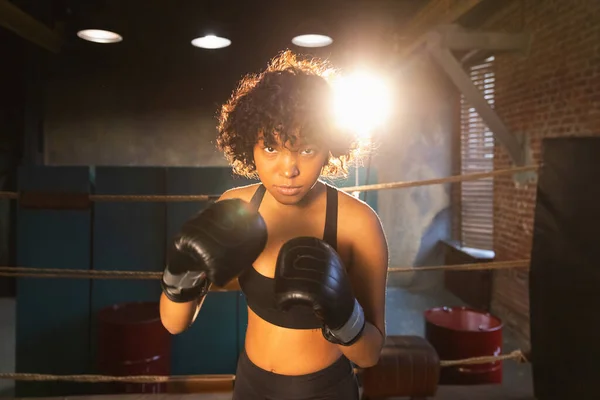Outcry independent girl power. Angry african american woman fighter with boxing gloves looking serious aggressive standing on boxing ring. Strong powerful fighter girl training punches