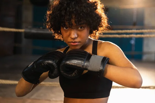 Outcry independent girl power. Angry african american woman fighter with boxing gloves looking serious aggressive standing on boxing ring. Strong powerful fighter girl training punches