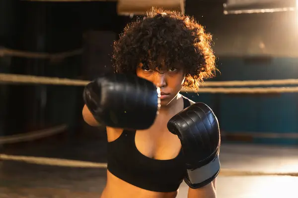 Women self defense girl power. African american woman fighter punching with boxing gloves to camera. Healthy strong girl punching training punches looking concentrated straight. Fit body workout