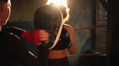 Kadınların savunma gücü. Kadın boksör ve spor salonunda kişisel antrenör eğitiminde annelik sporu eldivenleriyle yumruk atmayı öğretiyor. Sağlıklı güçlü kız antrenman yumruklarını yumrukluyor. Vücut çalışmasına uygun.
