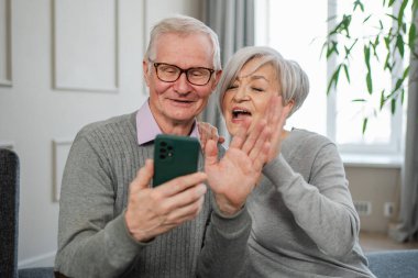 Görüntülü arama. Akıllı telefonlu mutlu son sınıf kadın erkek video görüşmesi yapıyor. Olgun yaşlı büyükbaba internette konuşuyor. Eski nesil modern teknoloji kullanımı. Sanal toplantı çevrimiçi sohbet