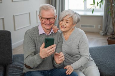 Görüntülü arama. Akıllı telefonlu mutlu son sınıf kadın erkek video görüşmesi yapıyor. Olgun yaşlı büyükbaba internette konuşuyor. Eski nesil modern teknoloji kullanımı. Sanal toplantı çevrimiçi sohbet