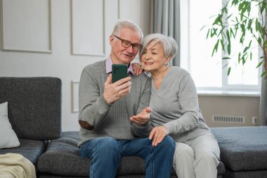 Görüntülü arama. Akıllı telefonlu mutlu son sınıf kadın erkek video görüşmesi yapıyor. Olgun yaşlı büyükbaba internette konuşuyor. Eski nesil modern teknoloji kullanımı. Sanal toplantı çevrimiçi sohbet