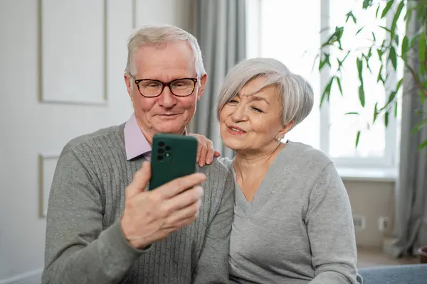 Video call. Happy senior couple woman man with smartphone having video call. Mature old grandmother grandfather talking speaking online. Older generation modern tech usage. Virtual meeting online chat