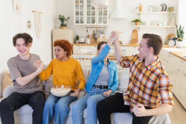 Bir grup arkadaş televizyonda futbol maçı izliyorlar. Memlekette zaferi kutlayan futbol taraftarları. Arkadaşlık sporu eğlence konsepti. Çeşitli arkadaşlar evde birlikte eğleniyorlar.