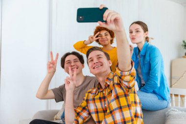 Keyfinize bakın. Mutlu arkadaş grubu selfie çekiyor. Partide arkadaşlarının fotoğrafını çeken bir adam. Telefonda fotoğraf çeken bir grup çok ırklı genç. Gençler gülümsemenin keyfini çıkarırlar.
