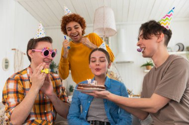 Bir dilek tut. Parti şapkası takan bir kadın doğum günü pastasında yanan mumları üflüyor. Doğum günün kutlu olsun. Bir grup arkadaş kızın doğum gününü kutluyor. İnsanlar doğum gününü evde partiyle kutluyor.