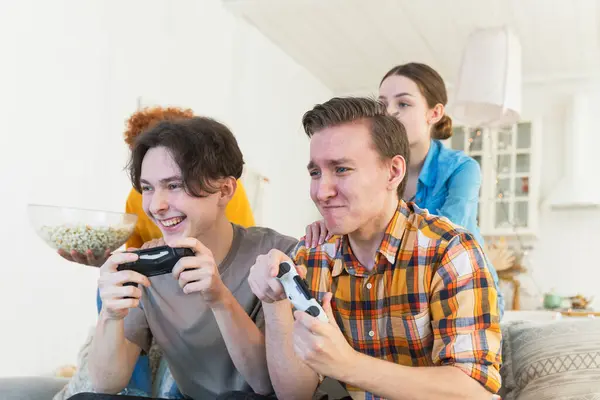 Home party. Cheerful group of friends playing video games at home. Happy diverse group buddies having fun together indoor. Friendship leisure entertainment concept. Young best friends enjoying weekend