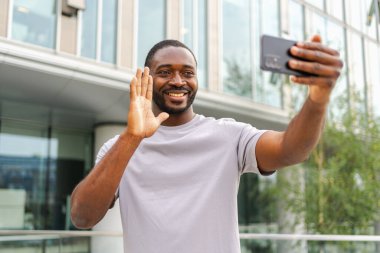 Afro-Amerikalı bir adam elinde akıllı telefonuyla şehirdeki bir caddede görüntülü konuşma yapıyor. Blogcu sosyal ağda en iyi arkadaşlarıyla sohbet ediyor. İnternette sanal görüşme yapan bir adam görüntülü konuşma yapıyor.