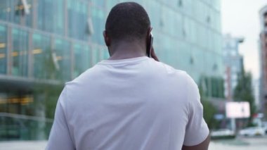 Arkaya bakan Afro-Amerikan adam dışarıda akıllı telefondan konuşuyor. Şehirde cep telefonu olan tanınmayan bir adam sokakta yürüyor. Cep telefonuyla cevap veren adam cep telefonuyla konuşuyor.