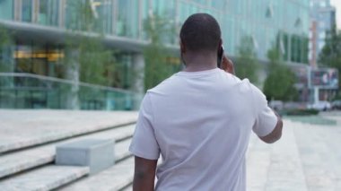 Arkaya bakan Afro-Amerikan adam dışarıda akıllı telefondan konuşuyor. Şehirde cep telefonu olan tanınmayan bir adam sokakta yürüyor. Cep telefonuyla cevap veren adam cep telefonuyla konuşuyor.