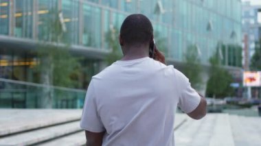 Arkaya bakan Afro-Amerikan adam dışarıda akıllı telefondan konuşuyor. Şehirde cep telefonu olan tanınmayan bir adam sokakta yürüyor. Cep telefonuyla cevap veren adam cep telefonuyla konuşuyor.