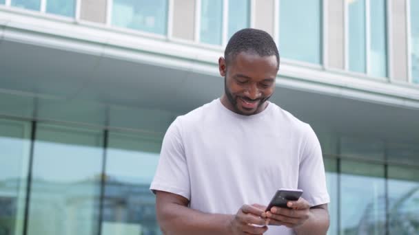 Afrykański Amerykanin Trzyma Ekran Dotykowy Smartfona Wpisując Przewijanie Strony Miejskiej — Wideo stockowe