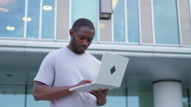 Afrikai Amerikai Férfi Szabadúszó Laptoppal Gépel Városi Utcában Egy Fickónak — Stock videók