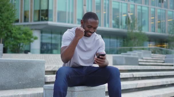 Glad Afroamerikansk Man Euforisk Vinnare Med Smartphone Gatan Stan Personen — Stockvideo