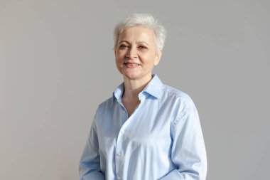 Kendine güveni tam, Avrupalı orta yaşlı, yaşlı bir kadın. 60 'lı yaşlarda beyaz arka planda gülümseyen olgun bir kadın. Mutlu, çekici, son sınıf öğrencisi, kamera görüntüsü, yüz portresi. Mutlu insanlar.