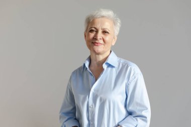 Kendine güveni tam, Avrupalı orta yaşlı, yaşlı bir kadın. 60 'lı yaşlarda beyaz arka planda gülümseyen olgun bir kadın. Mutlu, çekici, son sınıf öğrencisi, kamera görüntüsü, yüz portresi. Mutlu insanlar.