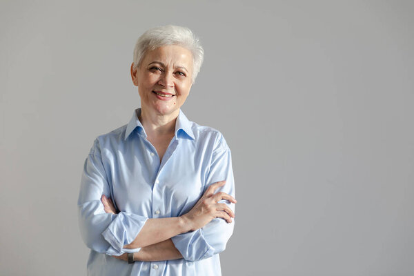 Уверенная стильная европейская старшая женщина средних лет. Пожилая женщина 60-х годов улыбается на белом фоне. Счастливая привлекательная пожилая женщина смотрит крупным планом на портрет. Счастливые люди