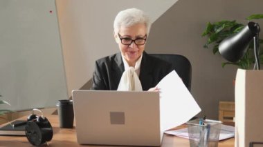 Orta yaşlı kıdemli patron, mali rapor raporlarını internette görüşüyor. Ofisteki olgun iş kadını dizüstü bilgisayarla proje fikirlerini konuşuyor.