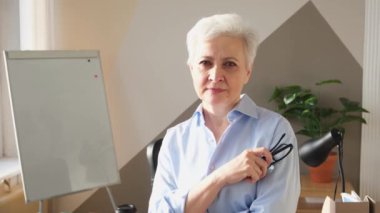 İş yerinde kendine güveni tam orta yaşlı Avrupalı bir kadının portresi. Modern ofisteki yaşlı, şık, 60 'lı yaşlarda, beyaz saçlı, bayan iş kadını. Patron öğretmen profesyonel işçi.