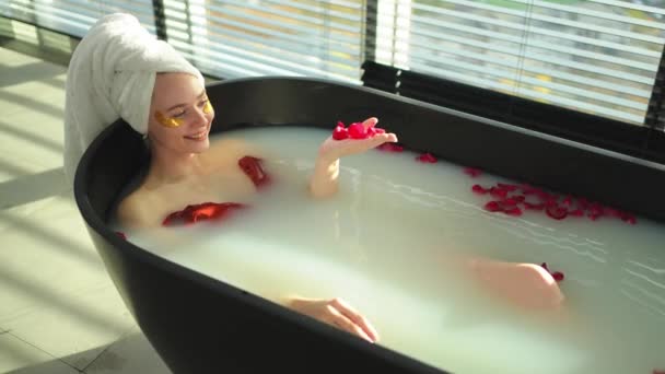 温泉放松 女人躺在浴池里 花瓣红红的 女孩在家里的浴室里放松 漂亮的女人喜欢洗热水澡 压力缓解 辛苦工作天后休息 — 图库视频影像