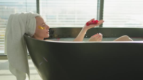 スパリラックス 赤いバラの花びらで入浴している女性 家でトイレでリラックスする女の子 熱いお風呂に入ることを楽しんでいるかなり女性 ストレス解消 一生懸命働いた後の休息 — ストック動画