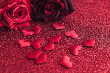 Sevgililer Günü konsepti. Kırmızı güller ve kırmızı parıltılı arka planda bir sürü kırmızı kalp. Sevgililer gününde kartpostal afişi. Aşk kaçamağı aşk evliliği aşk sembolü. Sevgililer Günü hediyesi.