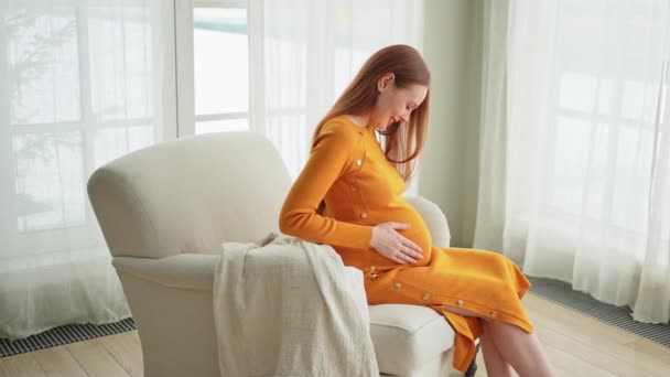 사람들은 미래를 기대합니다 집에서 근처의 의자에 임신을 즐기는 그녀의 부드러움 — 비디오
