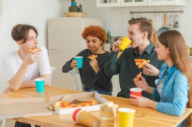Ev partisi. Arkadaşlar birlikte vakit geçirip gülerek ve evde iletişim kurarak eğleniyorlar. Bira ya da limonata içerek pizza yiyen mutlu bir grup. Karışık yarış genç dostları, en iyi arkadaşlar hafta sonunun tadını çıkarın.