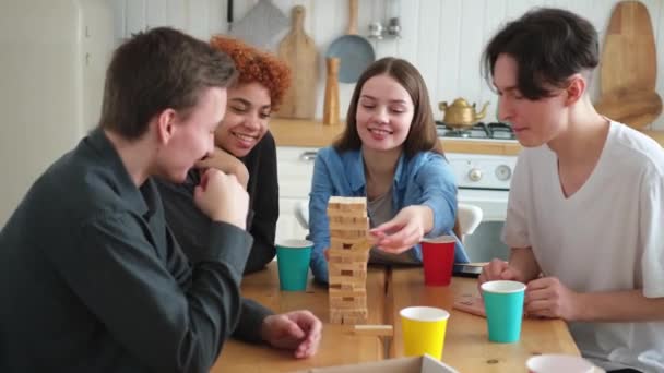 ホームパーティー 友達と一緒にボードゲームで遊ぶ時間を過ごす自宅で木製の塔をクラッシュします 屋内で一緒に楽しむ幸せな多様なグループ 混合レースの若い仲間最高の友人は週末を楽しんで — ストック動画
